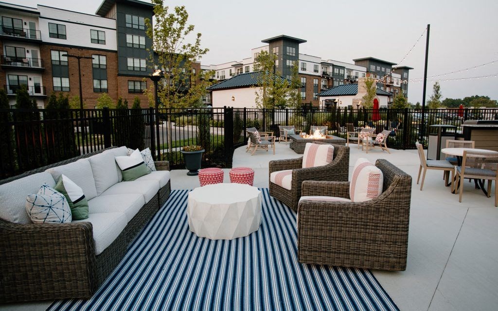 a patio with furniture and a table on a striped rug
