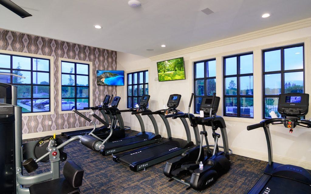 a gym with cardio equipment and windows