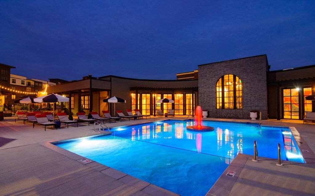 a swimming pool at night in front of a hotel