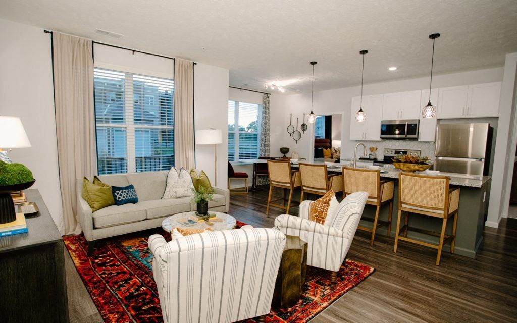 a living room and kitchen with a couch and chairs