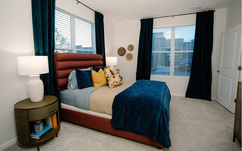 a bedroom with a bed and windows with curtains