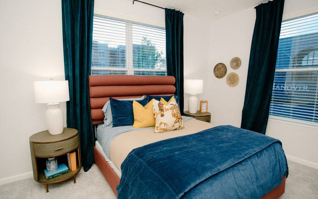 a bedroom with a bed and windows with blue curtains