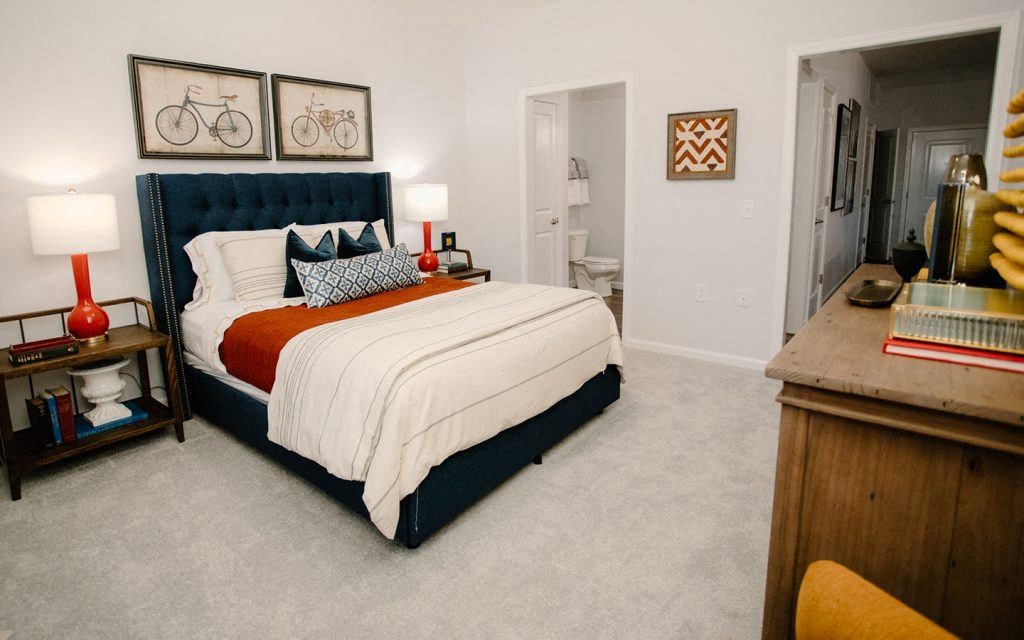 a bedroom with a bed and a dresser and a bathroom