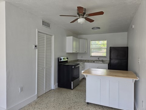 A kitchen with black appliances and white cabinets.