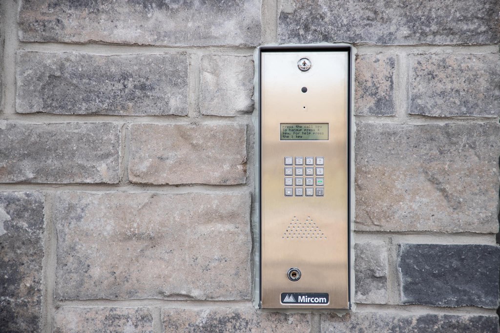 a stainless steel elevator control panel on a brick wall