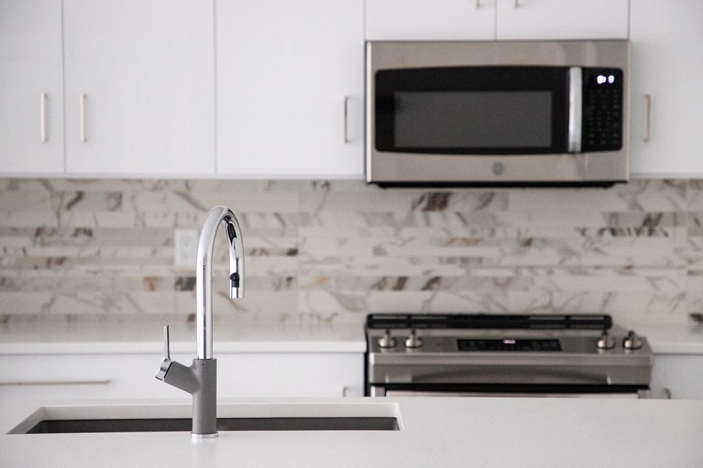 a white kitchen with a sink and a microwave