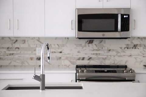 a white kitchen with a sink and a microwave