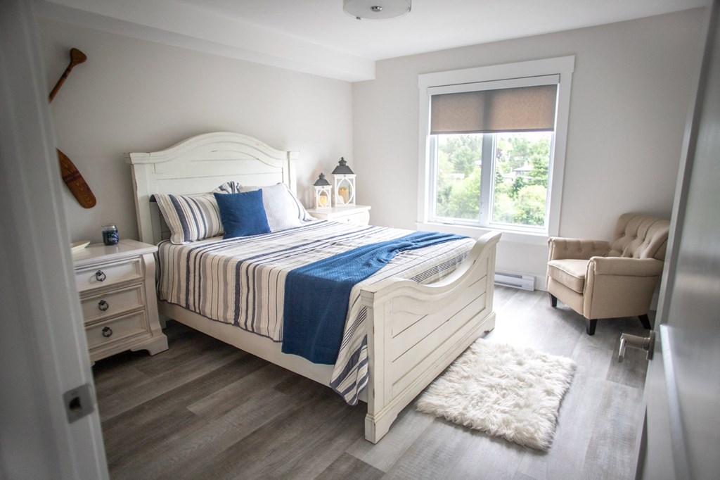 a bedroom with a bed and a chair and a window