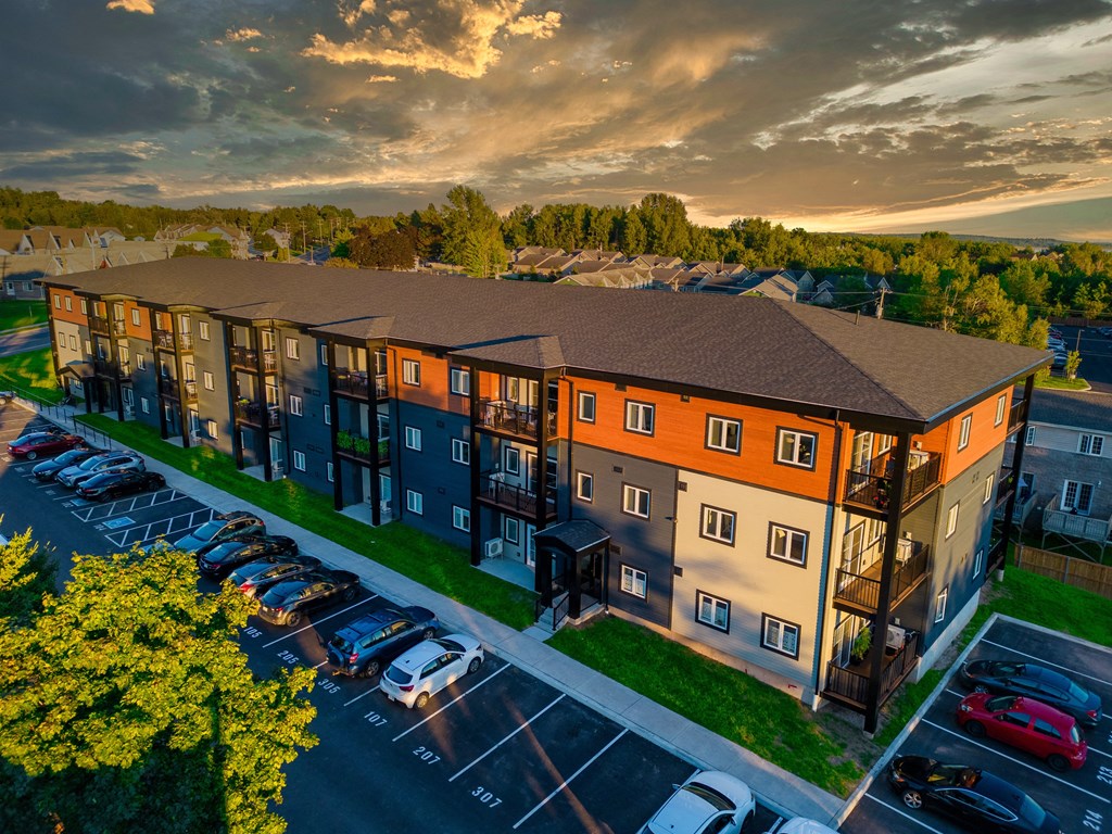 an aerial view of an apartment building with a sunset in the background