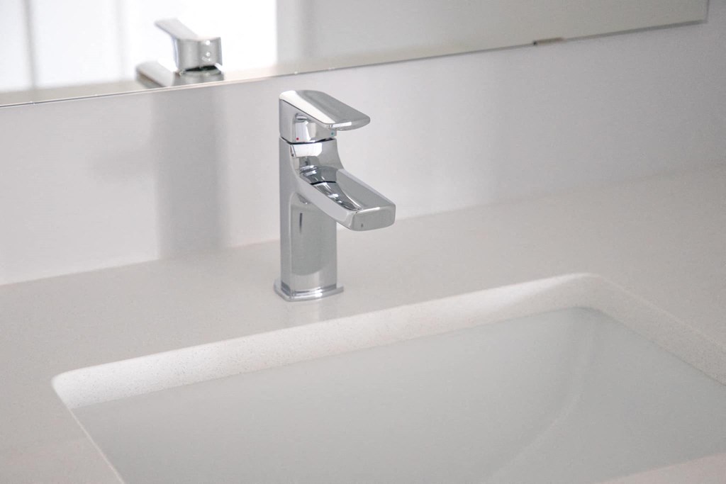 a white sink in a bathroom with a silver faucet
