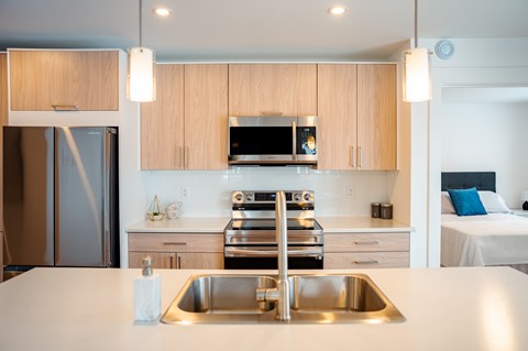 A modern kitchen with a stainless steel sink and wooden cabinets.