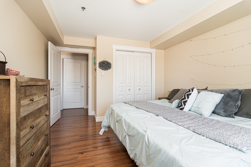 a bedroom with a bed and wooden floors and a dresser