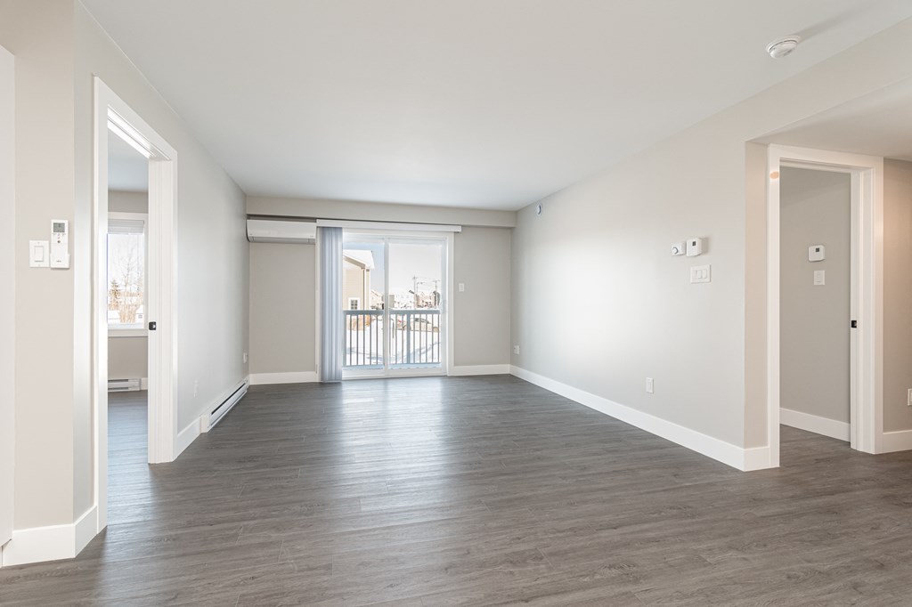 an empty living room with white walls and wood flooring