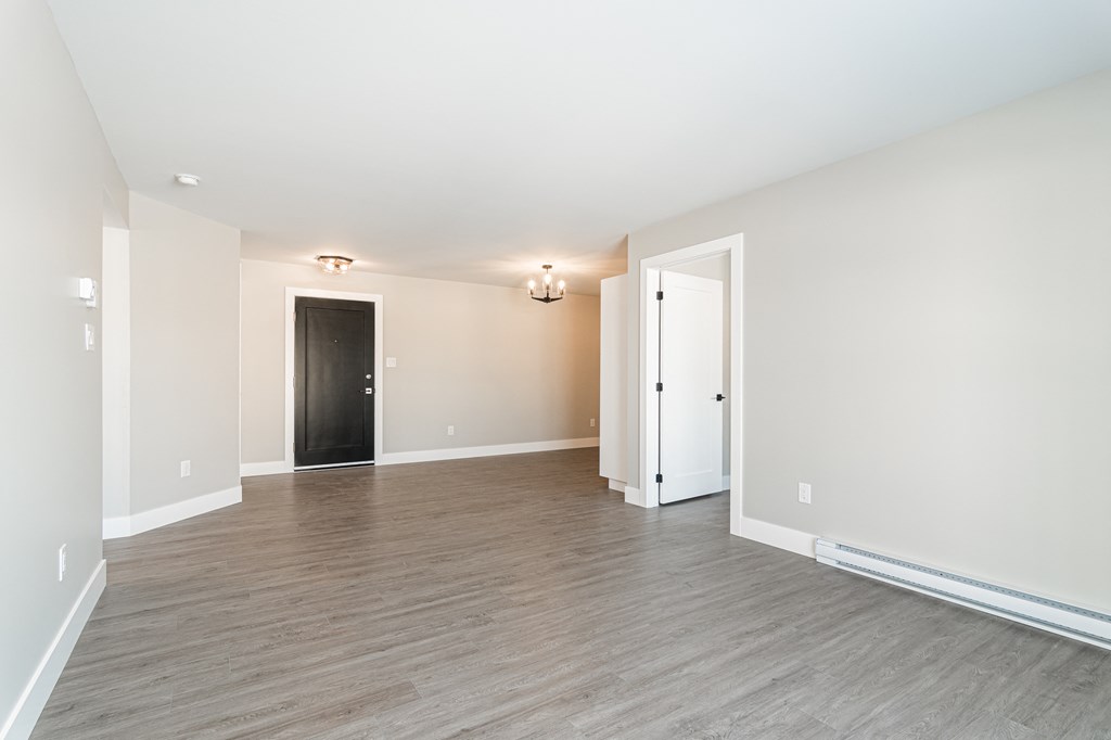 an empty living room with white walls and wood flooring