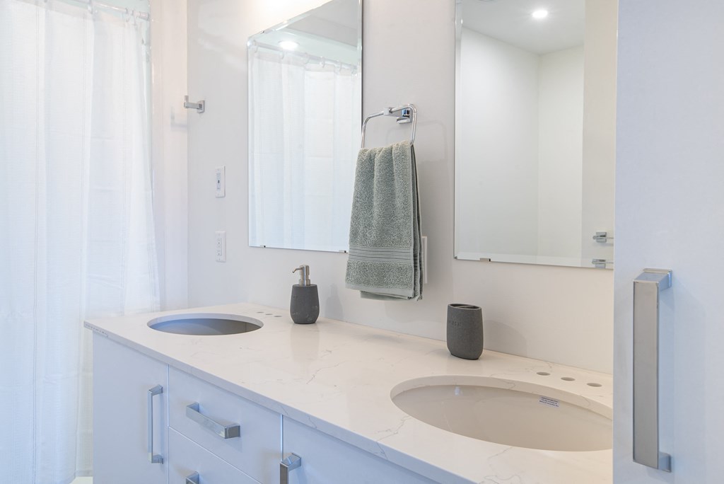 a white bathroom with two sinks and a mirror