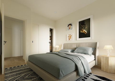 A bedroom with a bed, a lamp, and pictures on the wall.
