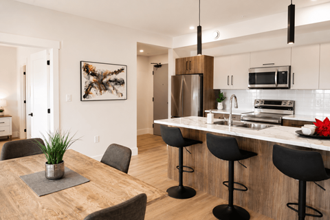 A modern kitchen with a wooden table and black bar stools.