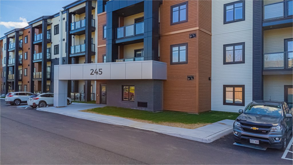 modern apartment building on the corner of a street with cars parked
