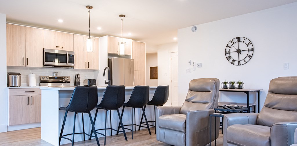 a living room with a kitchen and a counter with bar stools