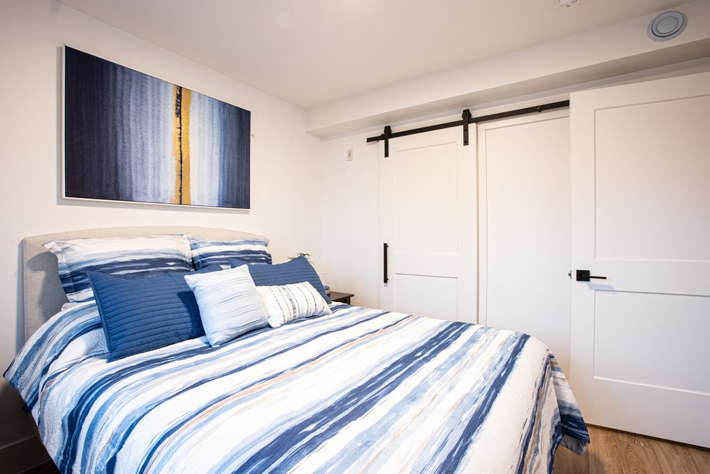 a bedroom with a bed with blue and white bedding and white closet doors