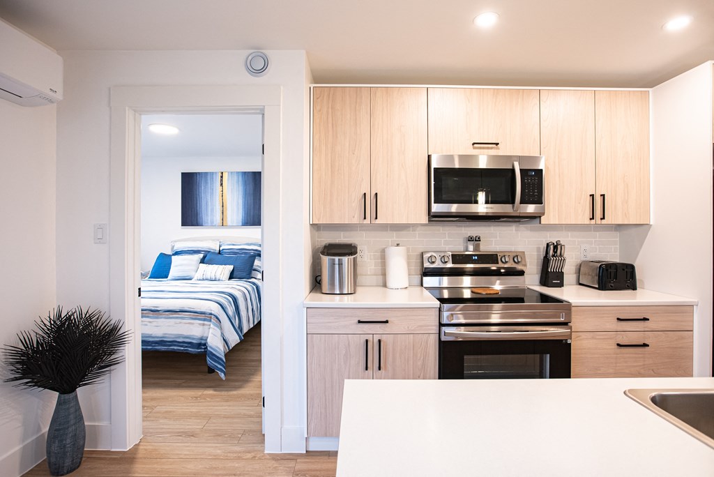 a kitchen and a bedroom with a bed and a microwave