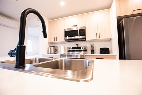 A kitchen with a sink and a black faucet.