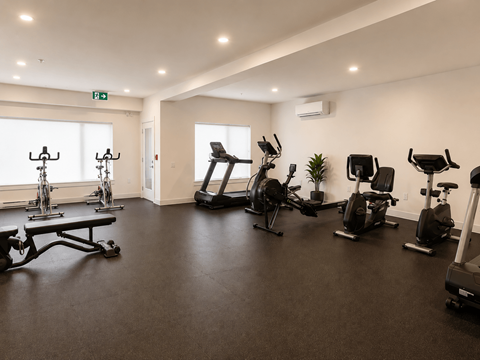 A gym with a variety of exercise equipment including treadmills, stationary bikes, and weight machines.