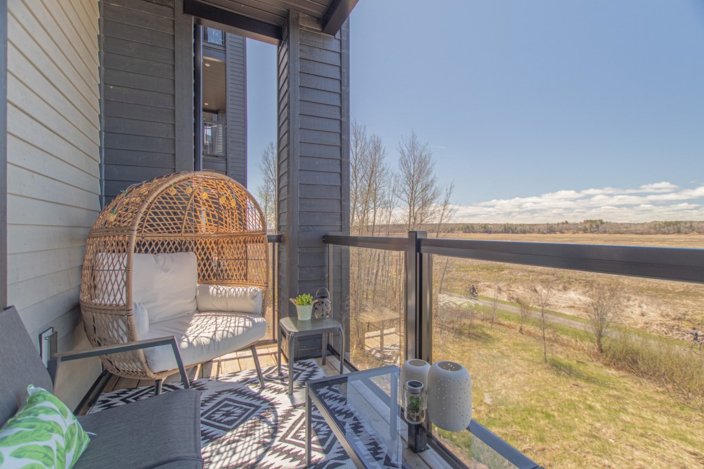the screened porch has a wickerickericker chair and a view of the water