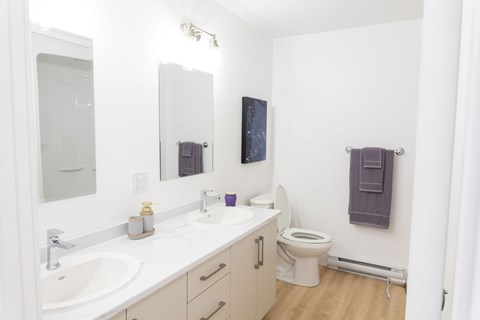 A white bathroom with a toilet, sink, and mirror.