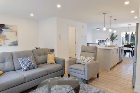 A grey couch with a grey and white pillow sits in a living room.