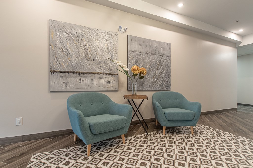 two blue chairs in a room with paintings on the wall