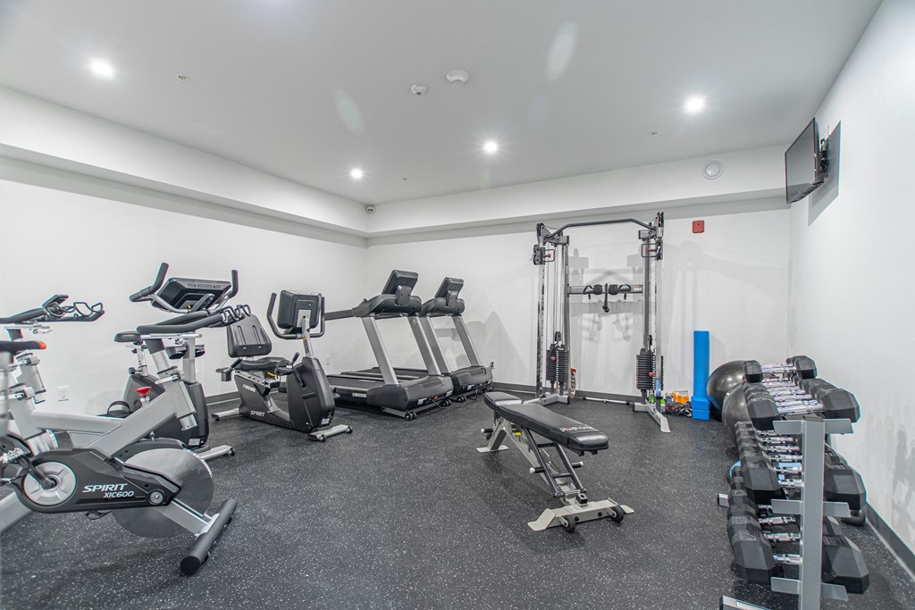 a gym with treadmills and other exercise equipment in a room with white walls