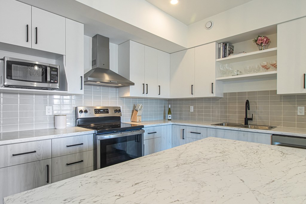 a kitchen with white cabinets and a marble counter top