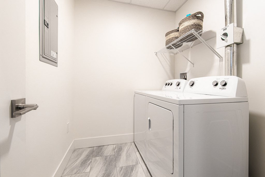 a white washer and dryer in a white laundry room with a sink