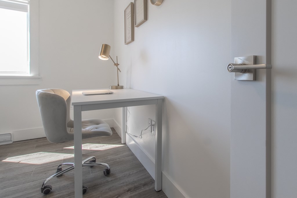 a desk in a room with a chair and a lamp