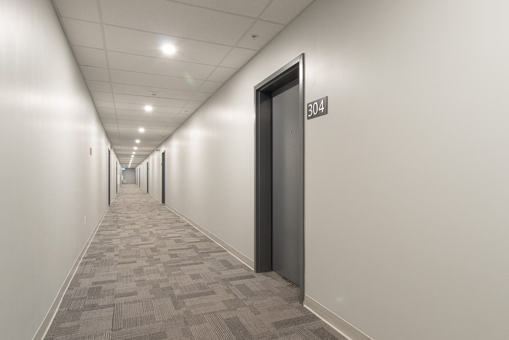 a long hallway with white walls and black doors