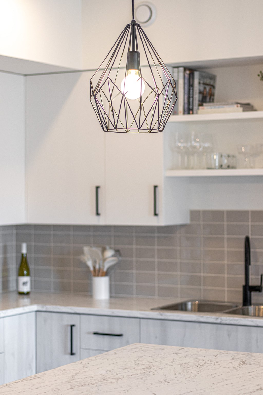 a kitchen with white cabinets and a counter top and a light hanging from the ceiling