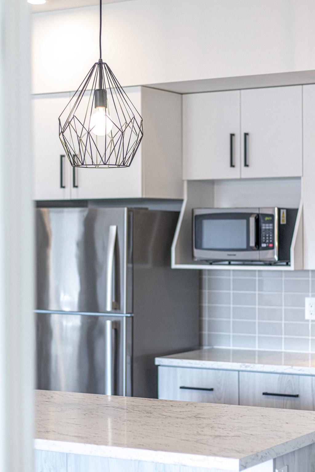 a white kitchen with stainless steel appliances and a quartz counter top