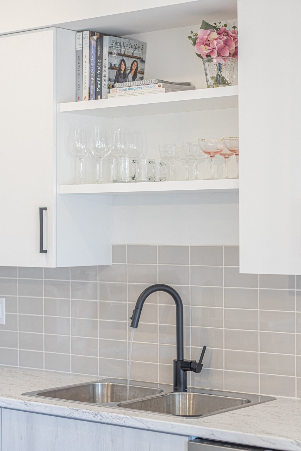 a kitchen sink with a black faucet and white tiles