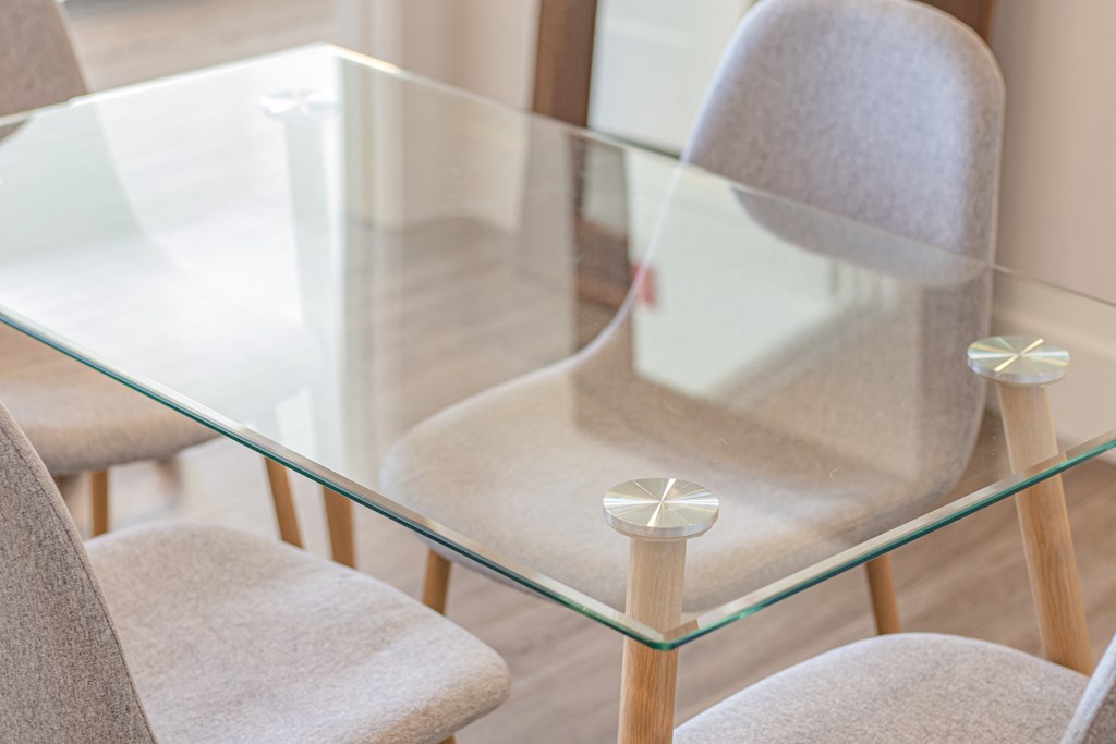 a close up of a glass table with four chairs