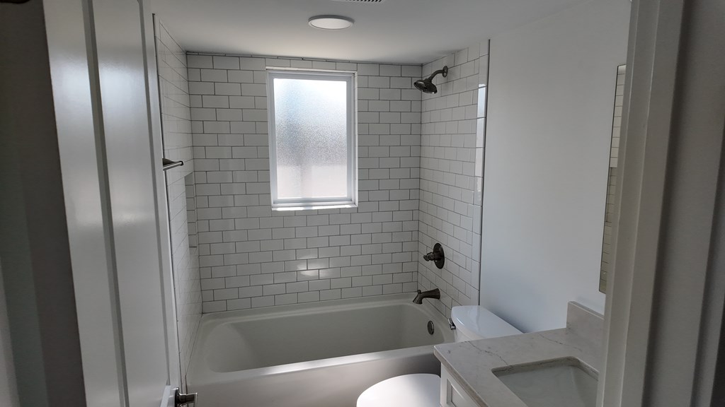 A white bathroom with a tub, sink, and shower.