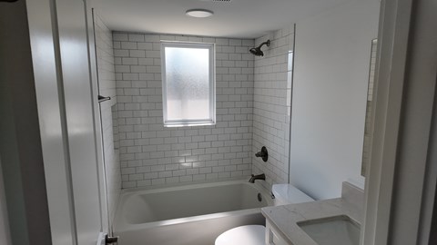 A white bathroom with a tub, sink, and shower.