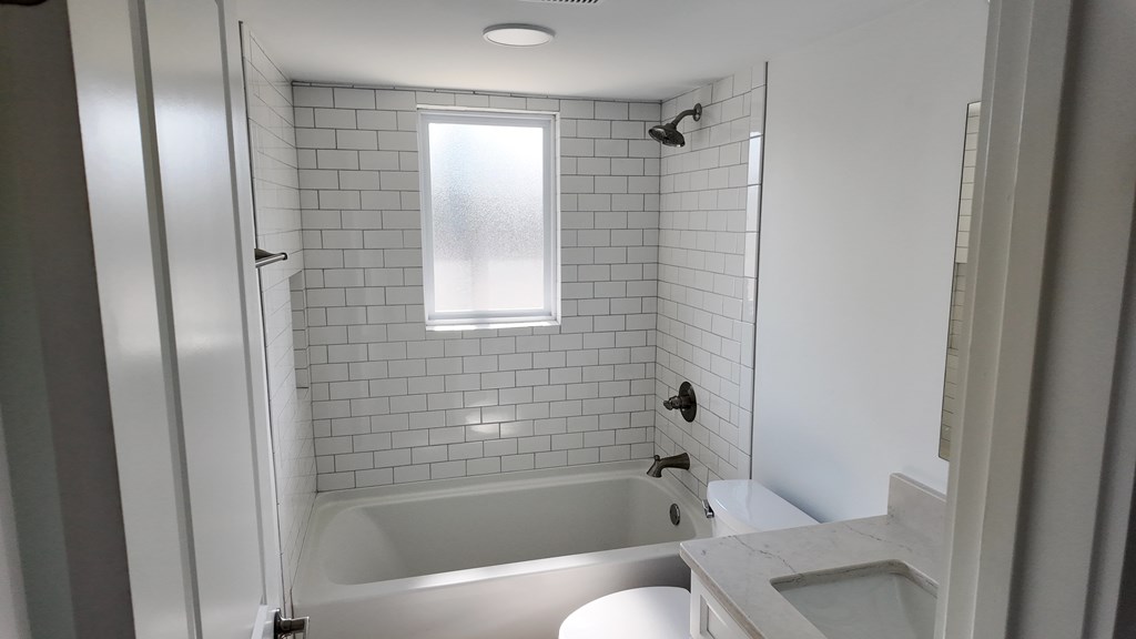 A white bathroom with a tub, toilet, and sink.