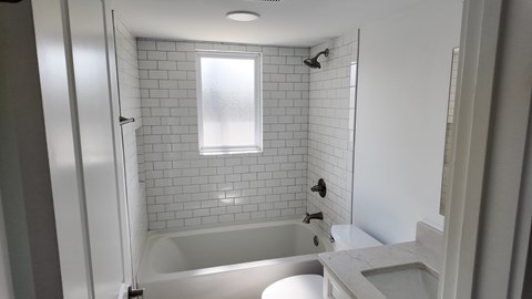 A white bathroom with a tub, toilet, and sink.