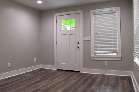 A room with a white door and a window with blinds.
