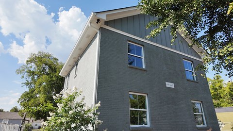 A grey house with a white window and a white sign on the front.