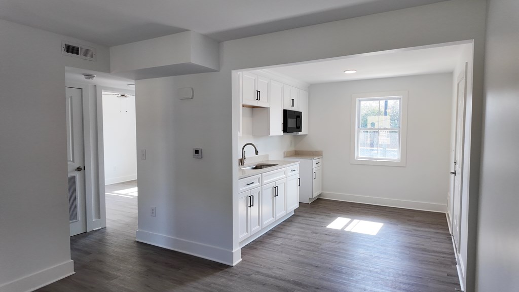 A kitchen with white cabinets and a window.