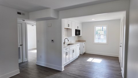 A kitchen with white cabinets and a window.
