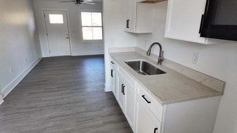 A kitchen with white cabinets and a marble countertop.