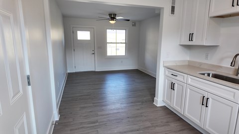 A kitchen with white cabinets and a wooden floor.